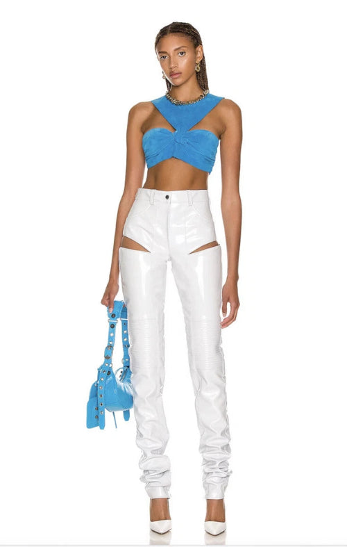 Woman wearing a blue top and white pants with a blue handbag on a white background