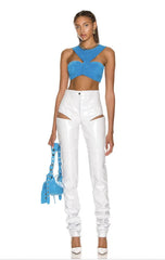 Woman wearing a blue top and white pants with a blue handbag on a white background