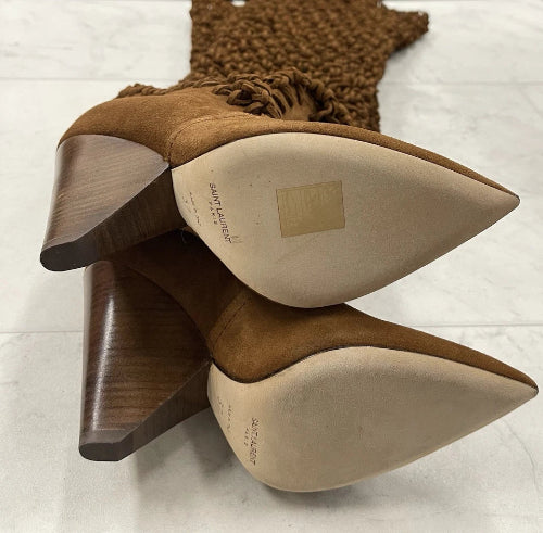 Pair of brown high-heeled shoes with visible brand name on a light background