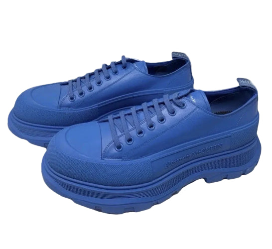 A pair of chunky low-top sneakers in a solid vibrant blue, featuring thick platform soles and matching blue laces, set against a plain white background.