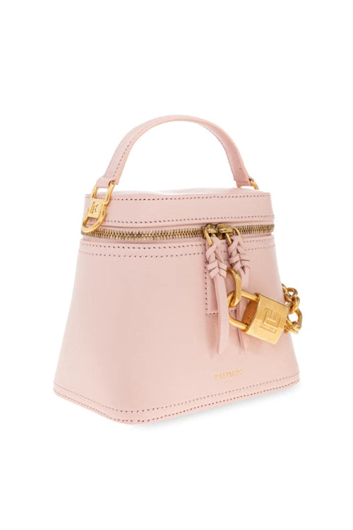 A light pink structured handbag with a top handle, gold-tone hardware, a zipper closure, and a decorative tassel with a padlock charm, shown on a plain white background.