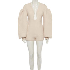 A light beige textured knit romper with dramatic puffed balloon sleeves and a deep plunging neckline, displayed on a white mannequin against a light gray background.