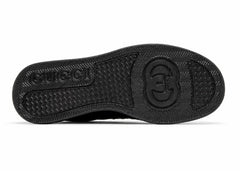 Black rubber outsole of a sneaker, showing the tread pattern and embossed logo on a plain white background.