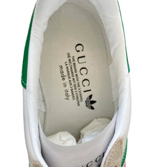 Close-up of the white interior lining of a Gucci sneaker, showing the brand name 'GUCCI' and the green trefoil logo printed on the insole.