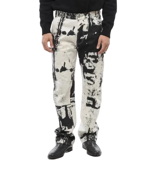 A person wearing black and off-white abstract print pants with a black long-sleeve top and black shoes, shown from the waist down against a light gray studio background.