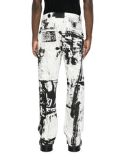 A person shown from the back wearing wide-leg trousers with an abstract black and white paint-splatter print, paired with a black top and black shoes, against a plain white studio background.
