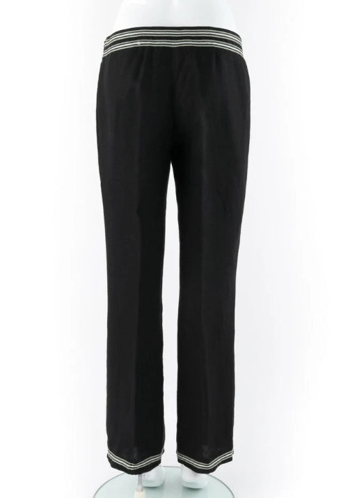 Black wide-leg trousers with contrasting striped trim at the elastic waistband and the bottom hems, displayed on a white mannequin against a white background.