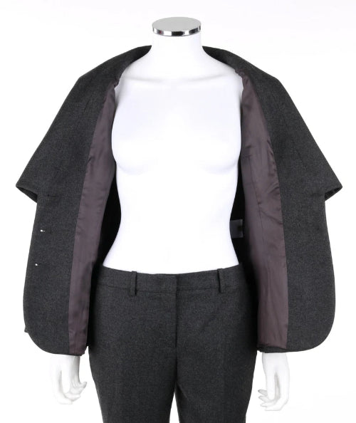 A dark gray wool cape jacket with a contrasting dark brown satin lining, displayed on a white mannequin torso with matching gray trousers.