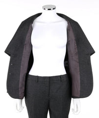 A dark gray wool cape jacket with a contrasting dark brown satin lining, displayed on a white mannequin torso with matching gray trousers.