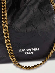 Black bag with gold chain and 'Balenciaga Paris' logo on a white background