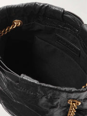 Close-up of a black handbag with gold chain details on a white background