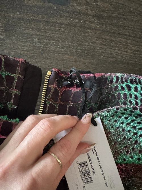 Close-up of a hand holding a patterned fabric with a visible brand label.