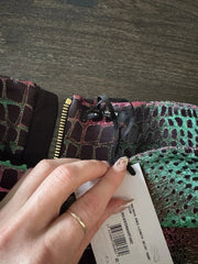 Close-up of a hand holding a patterned fabric with a visible brand label.