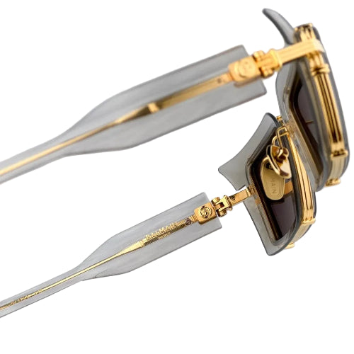 Sunglasses with gold frames and clear lenses on a light gray background