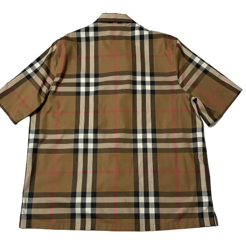 A short-sleeve plaid button-up shirt laid flat on a white background. The shirt features a classic check pattern in brown, beige, black, and white with thin red accent lines.