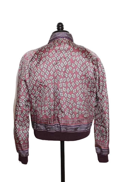 A long-sleeve patterned jacket displayed on a black dress form mannequin against a plain white wall. The jacket features a geometric diamond pattern in dusty pink, white, and dark purple, with a solid dark purple ribbed hem and cuffs.