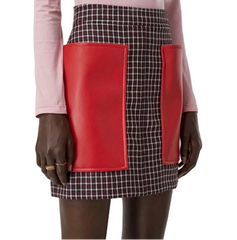 A model wearing a black and white gingham mini skirt with a prominent bright red leather front panel, styled with a pink top.