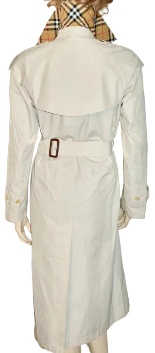 A light beige trench coat displayed on a mannequin, viewed from the back. The coat features a matching waist belt with a brown buckle.