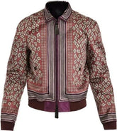 A patterned bomber jacket with a dusty rose base, featuring geometric diamond motifs and vertical stripes in cream, brown, and purple, with a dark purple ribbed hem and cuffs.