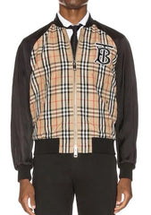 A Burberry men's bomber jacket featuring a beige and black check patterned front panel with a black embroidered 'B' logo, black sleeves and ribbed trim, shown on a model against a white background.