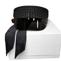 A black perforated leather belt with a matching black ribbon, presented on a white box.