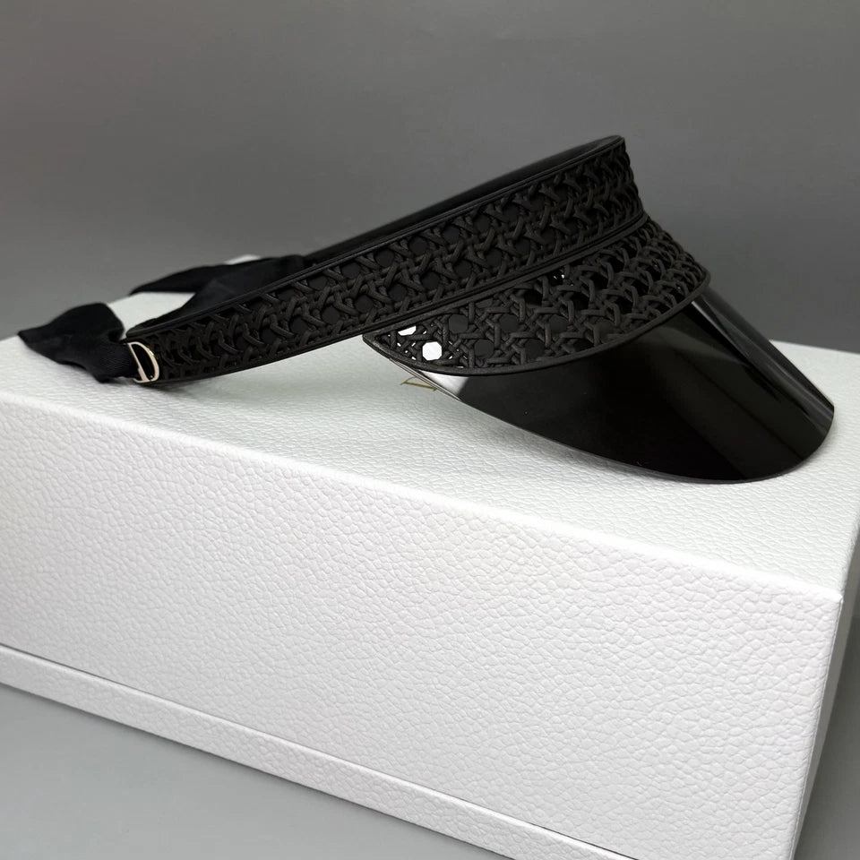 A black perforated leather slide sandal with a white box underneath, photographed on a neutral gray background.