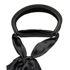 A black Dior visor hat with a matching black satin ribbon bow, displayed on a white textured box with the Dior logo visible inside the visor.