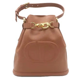 A brown leather bucket bag with a large embossed 'CD' logo on the front, gold-tone hardware, and a matching shoulder strap, shown against a plain white background.