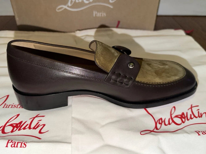 A single Christian Louboutin Paris loafer shoe in dark brown leather and tan suede, displayed on its white branded dust bag with the signature red script logo and a brown shoebox in the background.