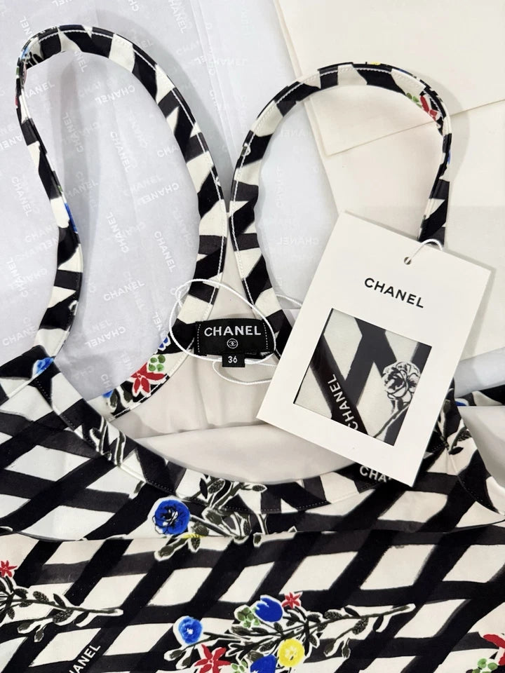 A black and white patterned pet collar with a matching fabric tag, displayed on a white surface with a black and white patterned fabric underneath.