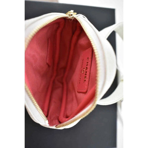 Close-up of a Chanel handbag with red interior and gold zipper.