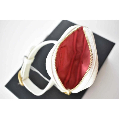 White pouch with gold zipper on a black surface