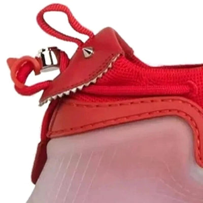 Close-up of a red and light pink shoe or boot showing the side panel, zipper, and red pull tab against a white background.