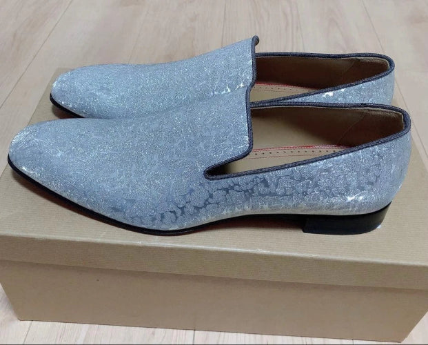Pair of blue glittery shoes on a beige box