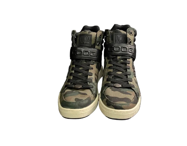 Camouflage high-top sneakers on a black stand against a dark brick wall.