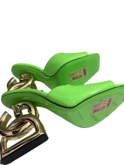 Green high-heeled shoes with gold chain detail on a white background