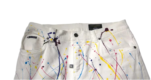 White denim jeans with colorful paint splatter and drip designs, shown against a plain gray background.