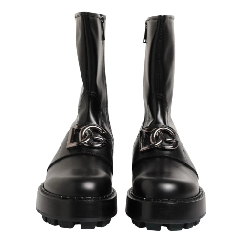 A pair of black leather ankle boots with chunky lug soles and side zippers, shown against a plain white background.