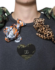 Person wearing a dark gray shirt with camouflage and leopard print plush toys on shoulders and a heart-shaped logo on chest.