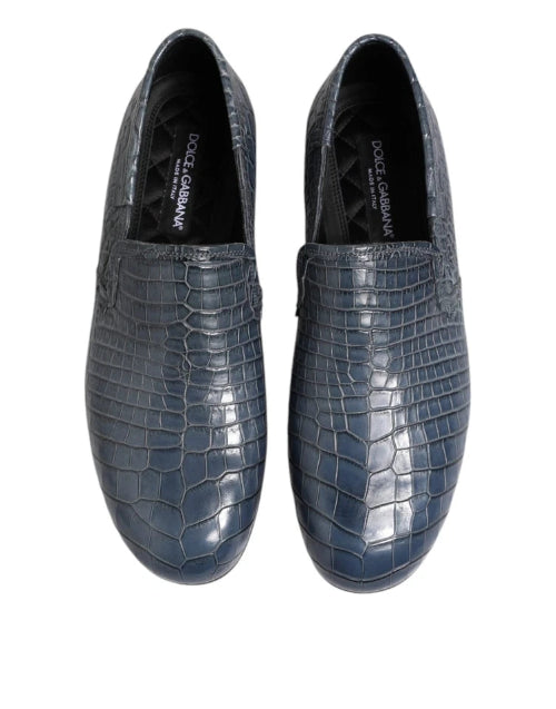 Pair of blue crocodile-textured loafers on a white background