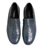Pair of blue crocodile-textured loafers on a white background