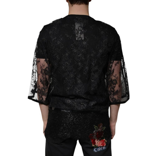 Black outfit with sheer sleeves and floral design on pants, worn by a person.