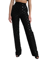 Black patterned pants worn by a person on a white background