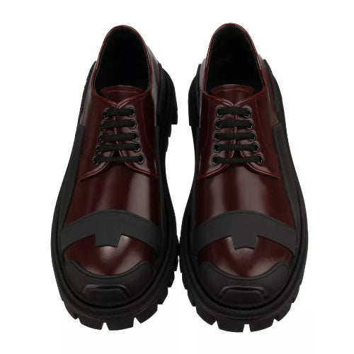 Pair of maroon shoes with black soles on a white background