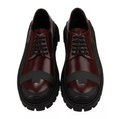 Pair of maroon shoes with black soles on a white background