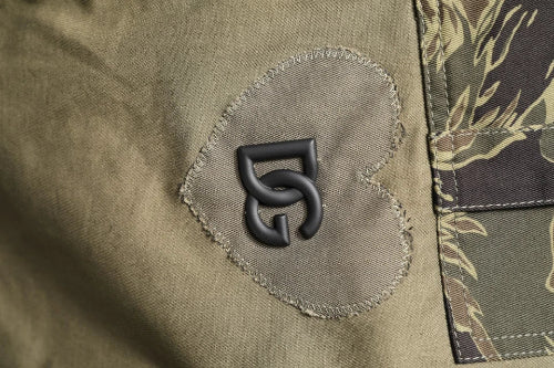 Close-up of a logo patch on a green jacket with a floral pattern.