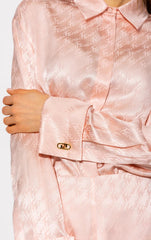Close-up of a pink satin blouse with a button detail.