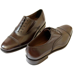 A pair of men's brown leather cap-toe oxford shoes with laces, displayed on a clean white background.