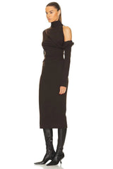 Woman wearing a black dress with long sleeves and black boots on a white background