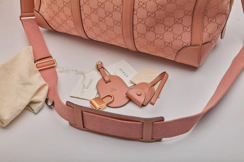 Pink Gucci bag with matching keychain and strap on a light gray background